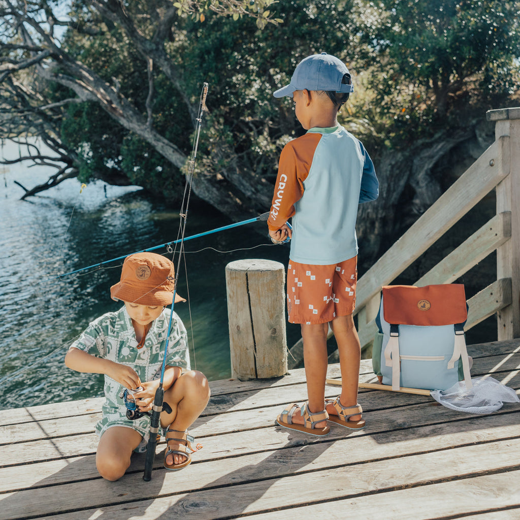 Two young children fishing on a dock wearing the CRYWOLF resort set, sandals, rash vest and board shorts.