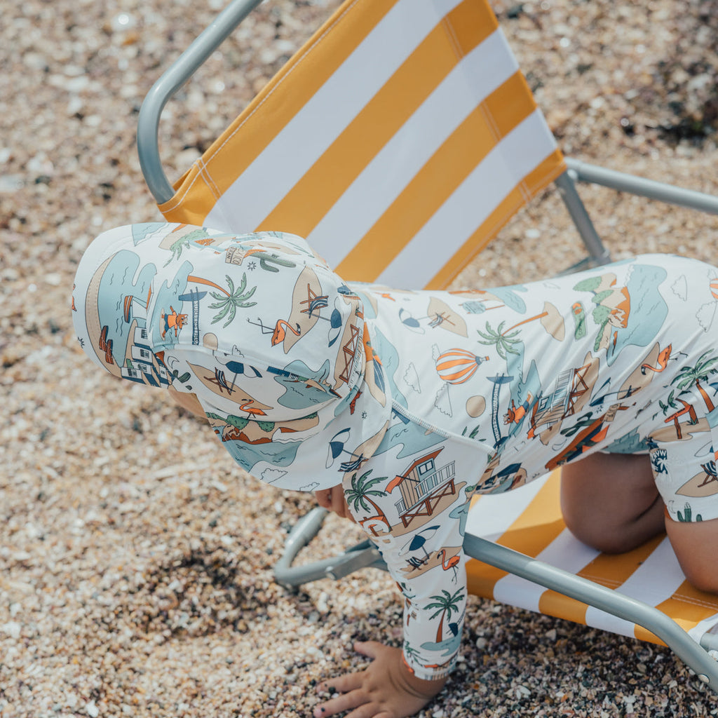 Picture of a small child playing on a sun chair on the beach while wearing a CRYWOLF Legionnaire sun hat.