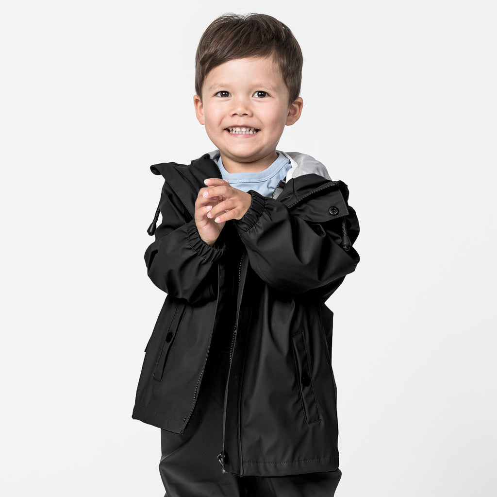 a Boy Smiling Wearing A Black Crywolf Classic Waterproof Play Jacket